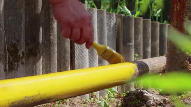 Primo piano maschio dipinge a mano un tubo arrugginito con vernice gialla. — Video Stock
