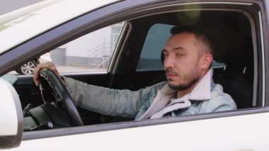 Modern, iş adamı gibi, genç bir adam mutlu bir şekilde gülümser, güler ve klasını gösterir..
