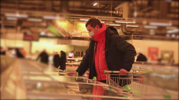 A man in a supermarket picks up mormite products with a mask on his face. — 비디오