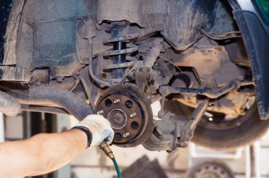 Eldivenli bir el, eski bir arabanın arka fren balatalarına sıkıştırılmış hava üfler..