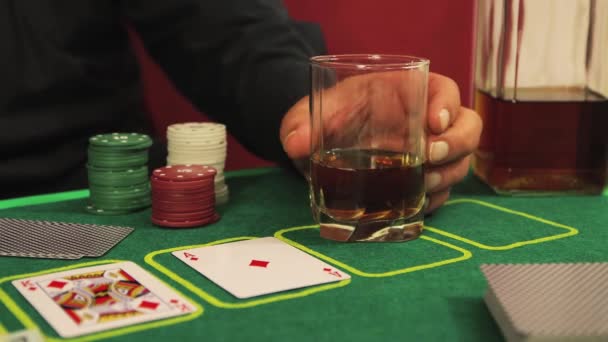 A mão dos jogadores close-up está girando um copo de uísque na mesa de cartas. — Vídeo de Stock