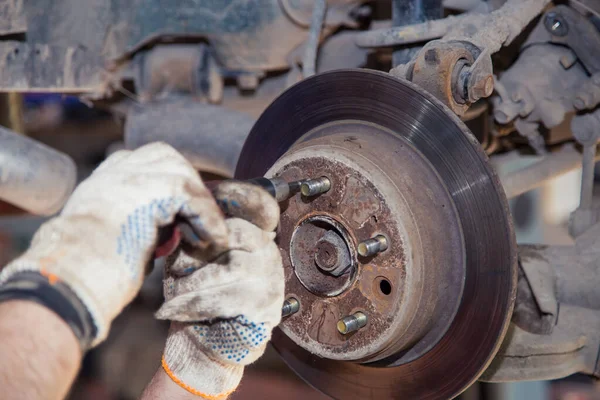 Eldivenli eller eski bir arabanın gövdesindeki vidaları sıkmak için tornavida kullanır..
