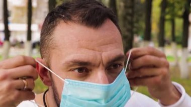 Tıbbi maske takan genç bir adamın yüzünü yakından çek..