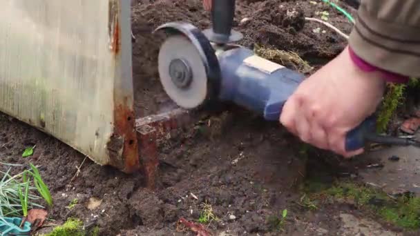 Les mains masculines coupent la structure métallique détruite avec une meuleuse. — Video