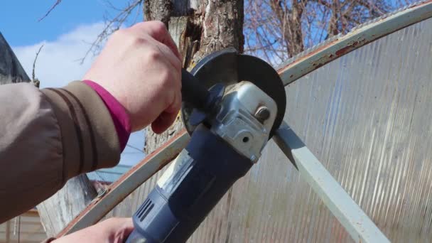 Male hands with a grinder cut a pipe against the background of the sky. — Stock Video