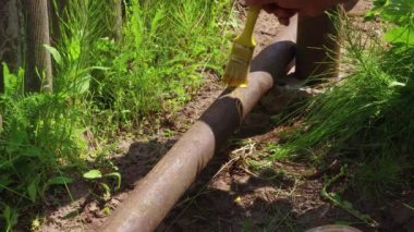 Bir adam sarı boyalı bir fırçayla pipo boyuyor..