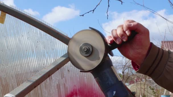 Mani maschili con un macinino tagliano una struttura metallica rotta contro il cielo blu. — Video Stock
