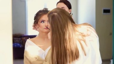 İki usta saç stili ve kirpikleri rimelle boyar.