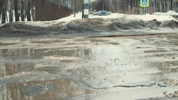 Agujeros en el asfalto, infraestructura vial dañada después de la precipitación. — Vídeos de Stock