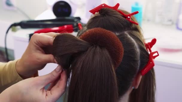 Maestri mani arricciare una ciocca di capelli, una ragazza in un salone di bellezza. — Video Stock