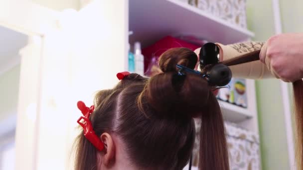 Ruce stočit kadeř vlasů s kleštěmi, dívka v salonu krásy. — Stock video