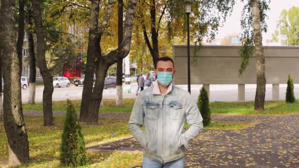 En ung man i medicinsk mask tittar på kameran och kommer närmare. — Stockvideo