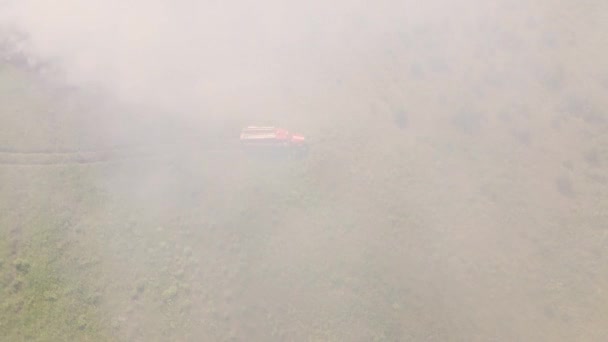 Na poli stojí hasičský vůz, zahalený kouřem z ohně.. — Stock video