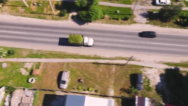 Een vrachtwagen beladen met verpletterd gras rijdt langs de weg, vanuit de lucht gezien. — Stockvideo