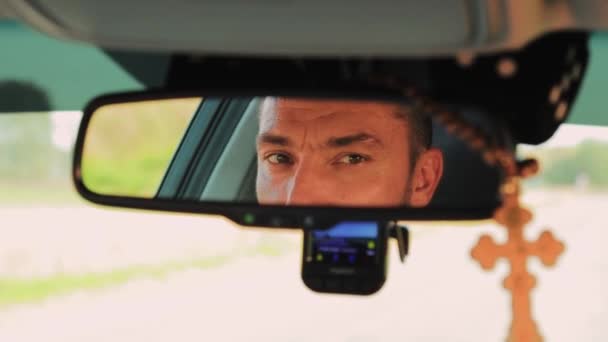 Um jovem homem olhos são refletidos no espelho retrovisor de um carro. — Vídeo de Stock