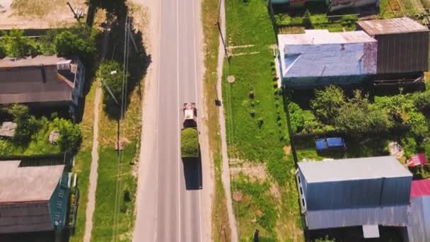 Nice aerial view of a tractor carrying a cart of grass along the road. — Stockvideo