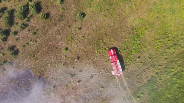 Un camión de bomberos envuelto en humo de un incendio en un campo. — Vídeos de Stock