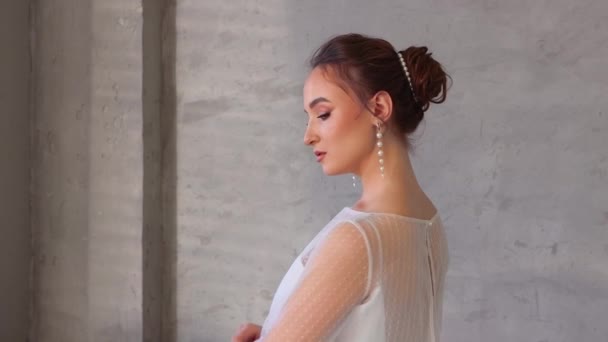Chica joven en un vestido blanco posando con la espalda vuelta. — Vídeos de Stock