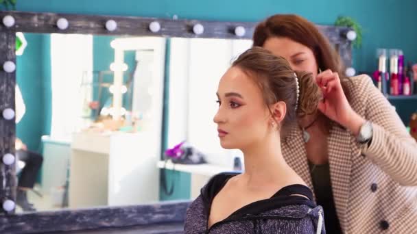 Uma jovem em um salão de cabeleireiro tem seu cabelo lindamente decorado. — Vídeo de Stock