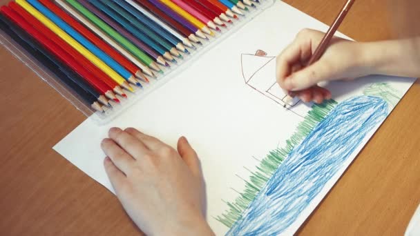 Dětské ruce kreslí dům na trávě u jezera. — Stock video