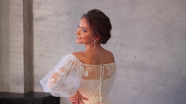 Чарівна молода дівчина в білій сукні красиво позує з її спиною . — стокове відео