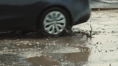 Yağmurdan sonra derin çukurlar, kötü hasar görmüş yol altyapısı.