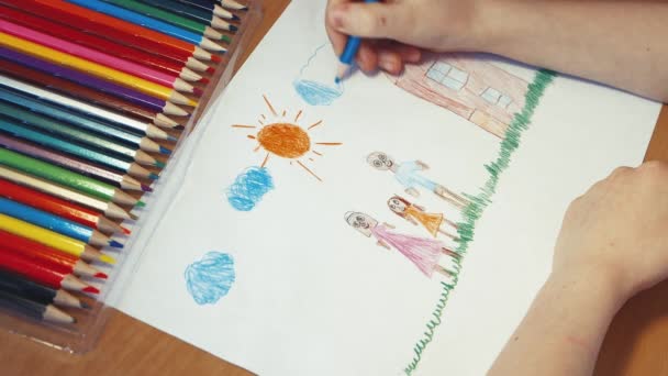 A childs hand draws blue clouds above the family next to the house. — Stock Video