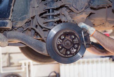 Eldivenli bir adamın elleri yıpranmış arka tekerlek göbek kalibresini söker.. 