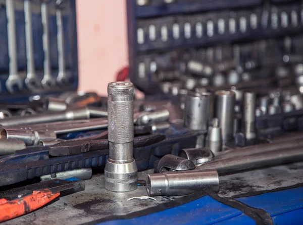 Un conjunto de enchufes para una llave, descentrado en un banco de trabajo de metal en un taller. — Foto de Stock