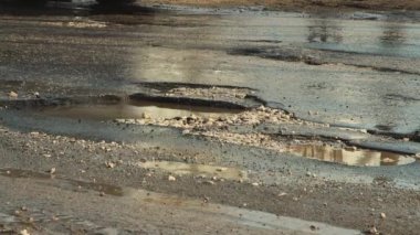 Asfalttaki kötü çukurlar, yağmurdan sonra hasar gören yol altyapısı.