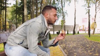 Modern genç adam lezzetli bir hamburger yiyor..