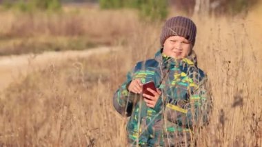 Çocuk telefonda konuşuyor ve ekranı gösteriyor, kameraya bakıyor..