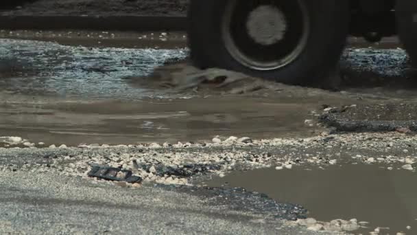 Veszélyes kátyúk vízzel rossz időben, súlyosan sérült közúti infrastruktúra. — Stock videók
