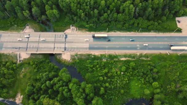 Вид с воздуха на грузовики и автомобили, быстро движущиеся по пригородному шоссе. — стоковое видео
