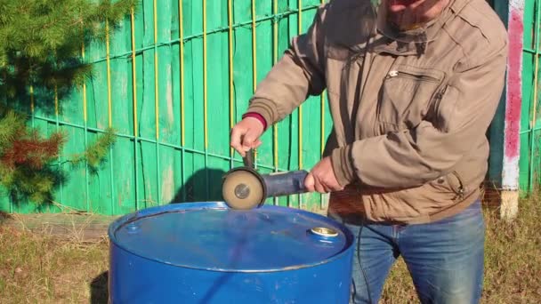 Een mensenhand snijdt een metalen vat met een haakse slijper. — Stockvideo