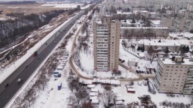 Kışın çok katlı binaları ve arabaları olan banliyö otoyolu, hava manzarası. 
