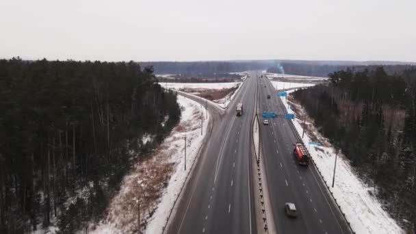 Široká příměstská dálnice s rychle se pohybujícími kamiony a automobily v zimě, letecký pohled. — Stock video