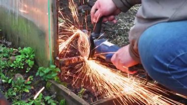 Bir açı öğütücüsüyle eller eski, parçalanmış metal yapıyı keser.. 