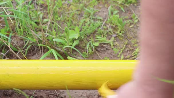 Eine Hand mit dem Pinsel in Großaufnahme bemalt ein rostiges Rohr mit gelber Farbe. — Stockvideo