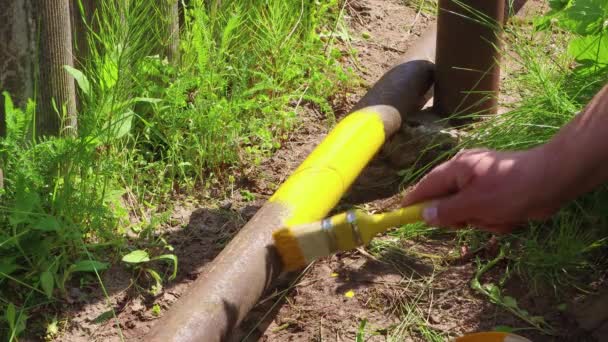 Una mano di mans dipinge un tubo con vernice in giallo con una spazzola. — Video Stock