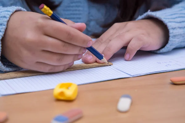 A student in a notebook works with a pencil with a ruler.