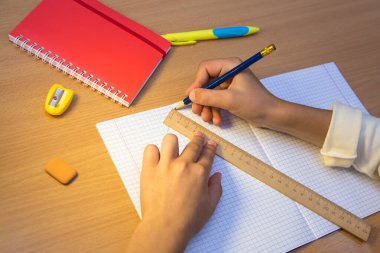 Not defterindeki bir öğrenci cetvel boyunca kurşun kalemle bir figür çizer.. 