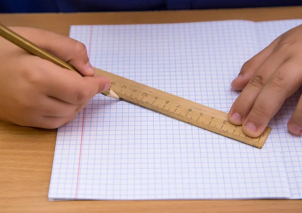 Студент малює пряму лінію олівцем уздовж лінійки . — стокове фото