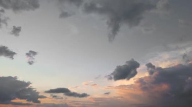 Koyu kırmızı-turuncu bulutlar mavi gökyüzüne karşı güneş ışığında.