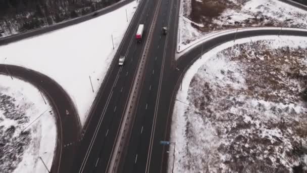 Autoroute de banlieue avec rond-point et voitures rapides en hiver, vue aérienne. — Video