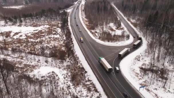 Αυτοκινητόδρομος με φορτηγά στροφή σε ένα παράλληλο δρόμο το χειμώνα, εναέρια άποψη — Αρχείο Βίντεο