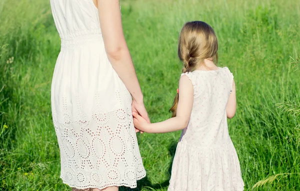 Menina no prado segurando sua mãe pela mão — Fotografia de Stock