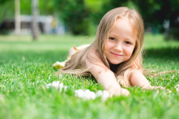 Schattig meisje ligt op het groene gras — Stockfoto