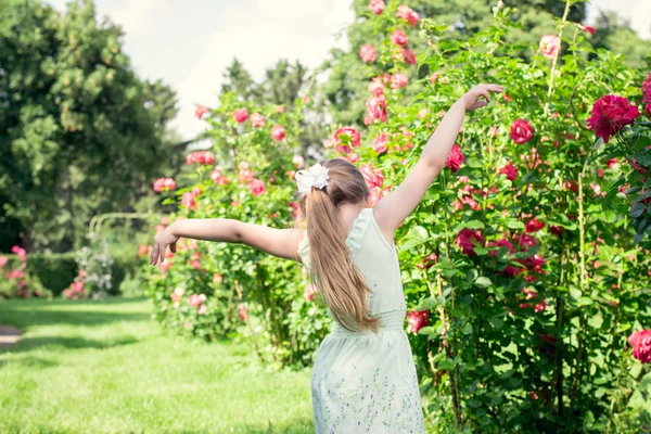 Klein meisje in de tuin verspreiden haar handen — Stockfoto