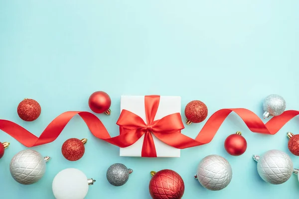 Mavi arka planda kırmızı ve gümüş süslemeli iki beyaz hediye kutusu. Noel arkaplanı. Düz konum, üst görünüm, kopyalama alanı. 